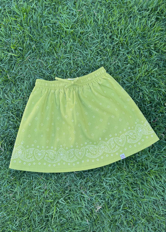 SOZO LAND Mini Skirt in Lime, featuring original Star Paisley print, a soft elastic waistband, playful flared silhouette and built-in shorts for easy movement, photographed flat on green grass.