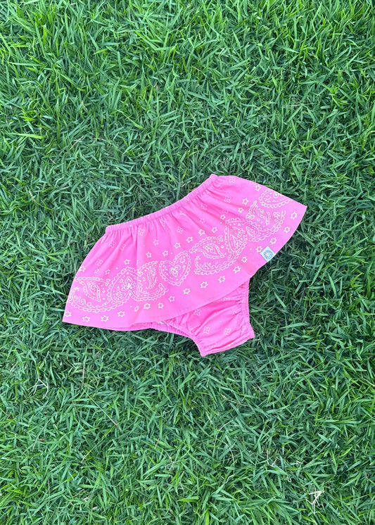 SOZO LAND Mini Bloomer in Bubblegum pink, featuring our signature Star Paisley print, a playful peplum skirt and built-in bloomers for comfortable movement, photographed flat on green grass.